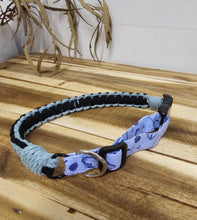Load image into Gallery viewer, A dog collar with a light blue and white patterned fabric, a black braided strap, and a brass ring, shown on a wooden background.