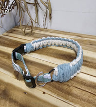 Load image into Gallery viewer, A handmade braided rope dog collar in light blue and white, featuring a black plastic buckle, silver metal ring, and patterned fabric tag, displayed on a wooden background.