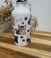 Load image into Gallery viewer, White water bottle with cat design and paw prints on a wooden surface