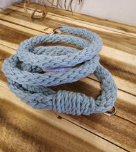 Load image into Gallery viewer, A light blue braided rope accessory with silver metal hardware, coiled on a wooden surface.