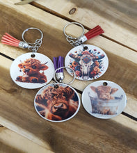 Load image into Gallery viewer, Set of keychains with animal designs on a wooden surface