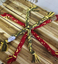 Load image into Gallery viewer, Four braided dog toys arranged in a cross pattern on a light wood plank background. The toys are made of braided red, olive green, and yellow rope with frayed ends.