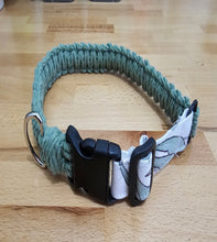 Load image into Gallery viewer, A handmade dog collar made of sage green Cotton with a black plastic quick-release buckle and a white patterned fabric lining, resting on a light wood surface.