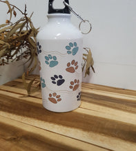 Load image into Gallery viewer, White water bottle with colorful paw prints on a wooden surface