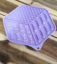 Load image into Gallery viewer, Purple Lick Mat with bone-shaped cavities on a wooden surface