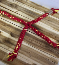 Load image into Gallery viewer, A braided rope pet toy in red and yellow, laid out in a cross shape on a rustic wooden plank background.