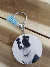 Load image into Gallery viewer, Keychain with a circular tag featuring a Border Collie design on a wooden surface