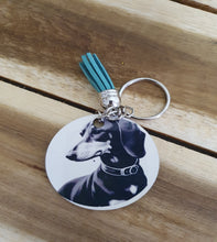 Load image into Gallery viewer, Keychain with a circular tag featuring a dog's face on a wooden surface