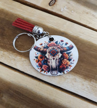 Load image into Gallery viewer, Keychain with colorful skull design and red tassel on a wooden surface