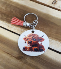 Load image into Gallery viewer, Keychain with baby Cow with Coffee design and tassel on a wooden surface