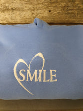 Load image into Gallery viewer, Blue jumper with white embrodiered white text &quot;Smile&quot; with a heart
