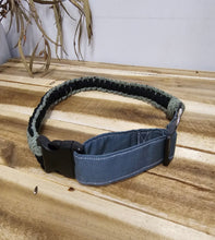 Load image into Gallery viewer, A green and Black-style collar with a black plastic buckle and a braided cord collar, shown on a light wood background.
