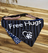 Load image into Gallery viewer, A navy blue striped pet bandana collar with white text reading 'Free Hugs' and a paw print graphic, displayed on a wooden surface.
