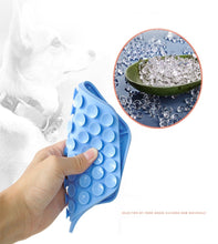 Load image into Gallery viewer, Blue silicone lick mat held by a hand with close-up of silicon on a white background.
