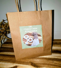 Load image into Gallery viewer, Brown paper bag with a green label featuring text and images on a wooden surface.
