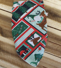 Load image into Gallery viewer, Fabric swatch with Christmas-themed pattern on a wooden surface
