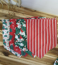 Load image into Gallery viewer, Stack of red and green patterned Dog Bandana on a wooden surface
