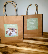 Load image into Gallery viewer, Two brown paper bags with green labels on a wooden surface.
