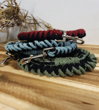 Load image into Gallery viewer, Three braided dog leashes in red, blue, and green hanging on a wooden surface.
