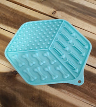 Load image into Gallery viewer, Aqua Lick Mat with bone-shaped cavities on a wooden surface
