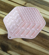 Load image into Gallery viewer, Pink Lick Mat with bone and fish patterns on a wooden surface
