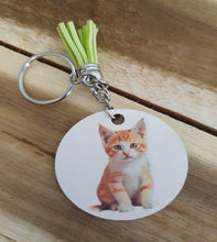 Load image into Gallery viewer, Keychain with a round tag featuring a cat illustration on a wooden surface
