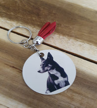 Load image into Gallery viewer, Keychain with a circular tag featuring a K illustration on a wooden surfacelpie
