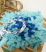Load image into Gallery viewer, Blue and turquoise snuffle mat with a rope toy in the center on a wooden surface.
